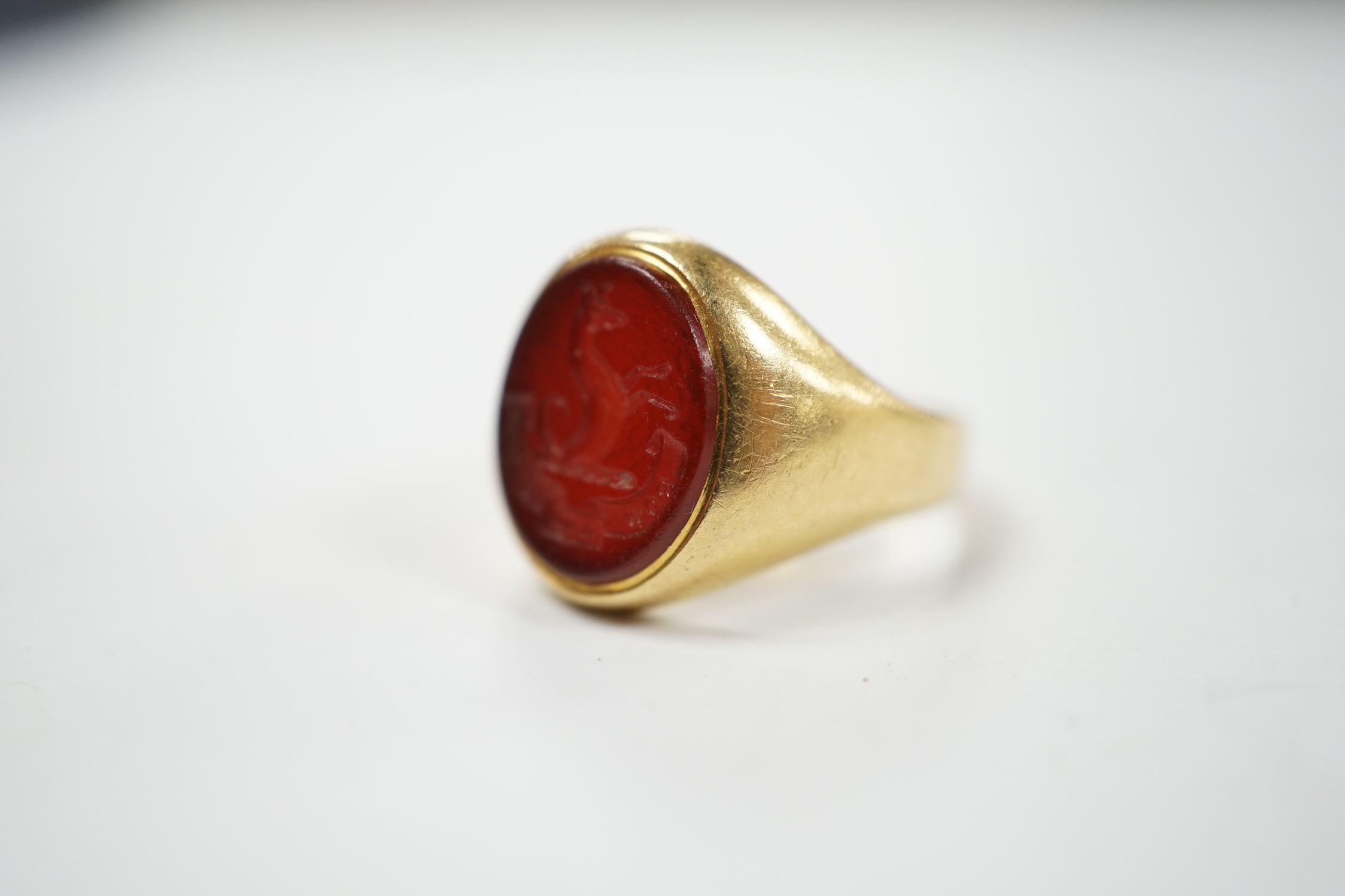 An 18ct and oval intaglio carnelian set signet ring, carved with family crest and motto, size K, gross weight 6.9 grams.